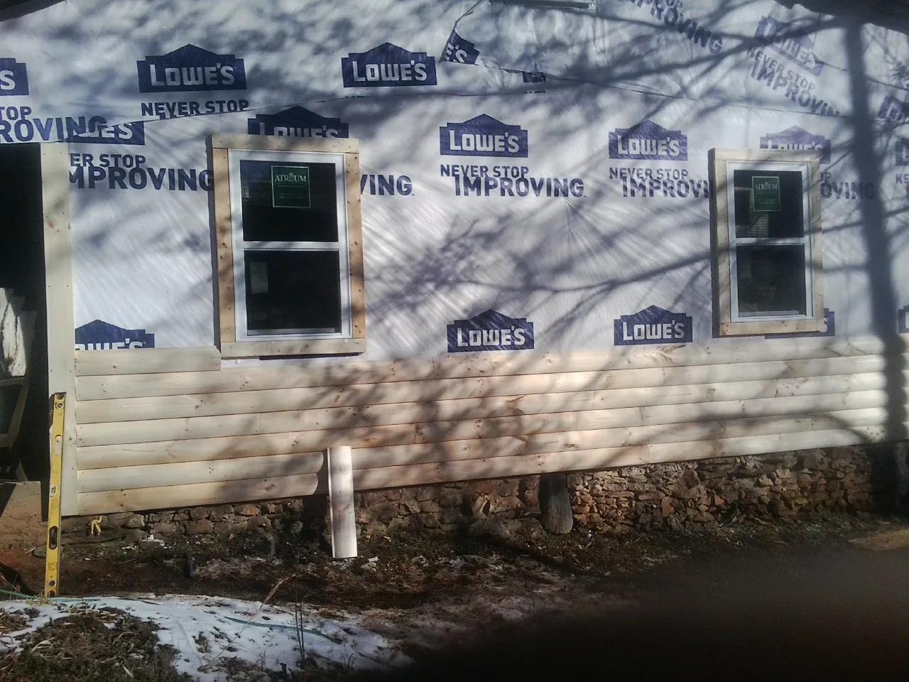 House wrap and new log siding going up on an exterior wall in Skull Valley