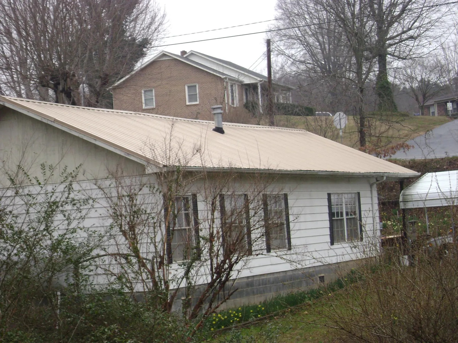 Tan metal roof on a white sided house set into a hillside — Commercial Roofing by Roofing Brothers in Skull Valley