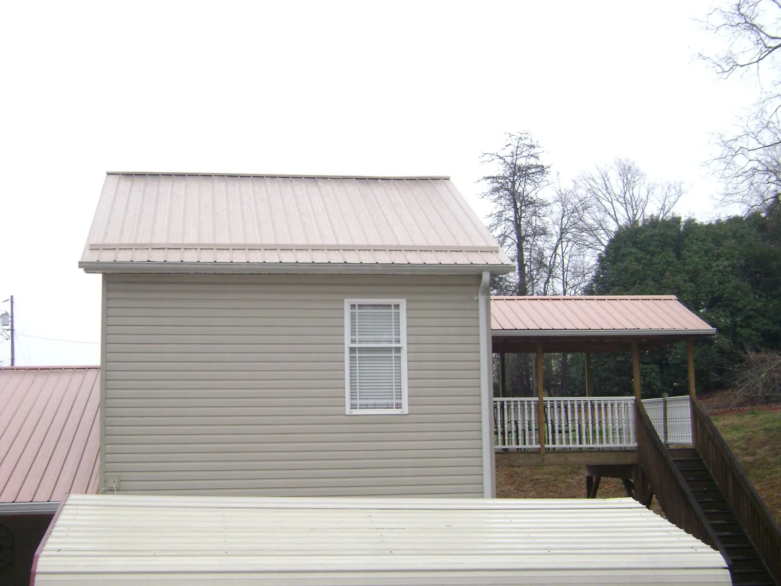 Tan metal roofs on a two story addition and attached porch, from a Roof Replacement job in Skull Valley